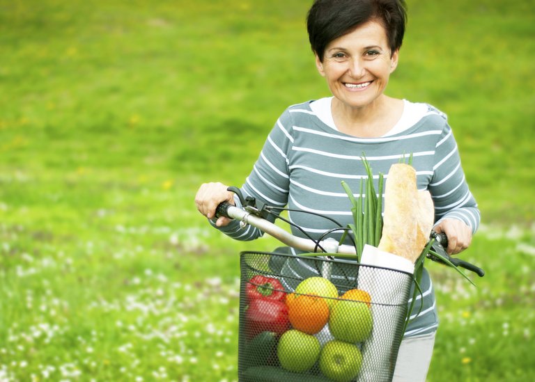[Translate to Turkey Turkish:] Woman on a bike with healthy food in the basket