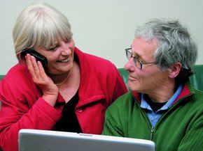 Dizüstü bilgisayar önünde kadın telefonda konuşurken birbirine bakan yaşlı çift